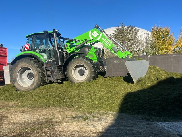 Traktor mit Siloschild beim Schieben von Grassilage am Fahrsilo